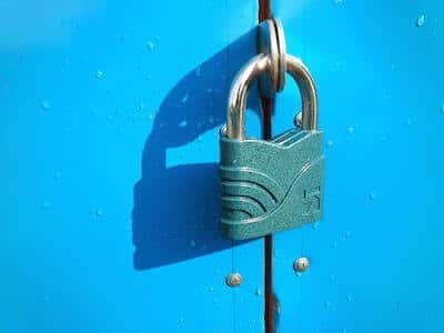 A green padlock keeps a bright blue cabinet door closed from unwanted guest
